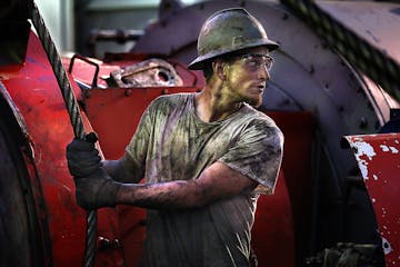 Floor hand Ray Gerrish worked to make repairs on a drilling rig as the sun rose near the site outside Watford City on December 17, 2013.