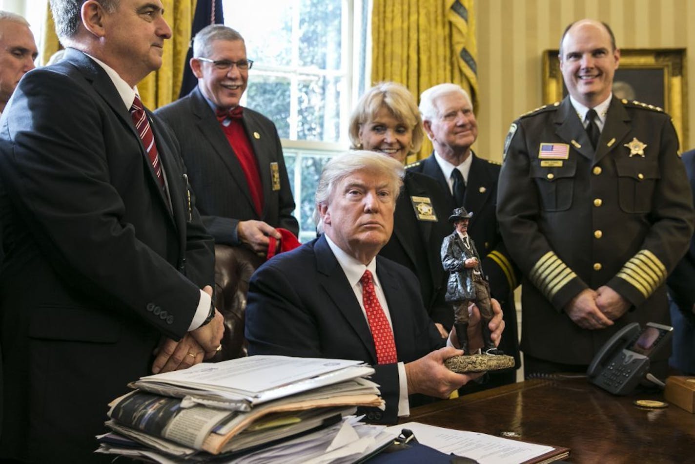 President Donald Trump holds a figurine given to him during a meeting with a group of sheriffs, in the Oval Office of the White House in Washington, Feb. 7, 2017.