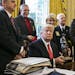 President Donald Trump holds a figurine given to him during a meeting with a group of sheriffs, in the Oval Office of the White House in Washington, F