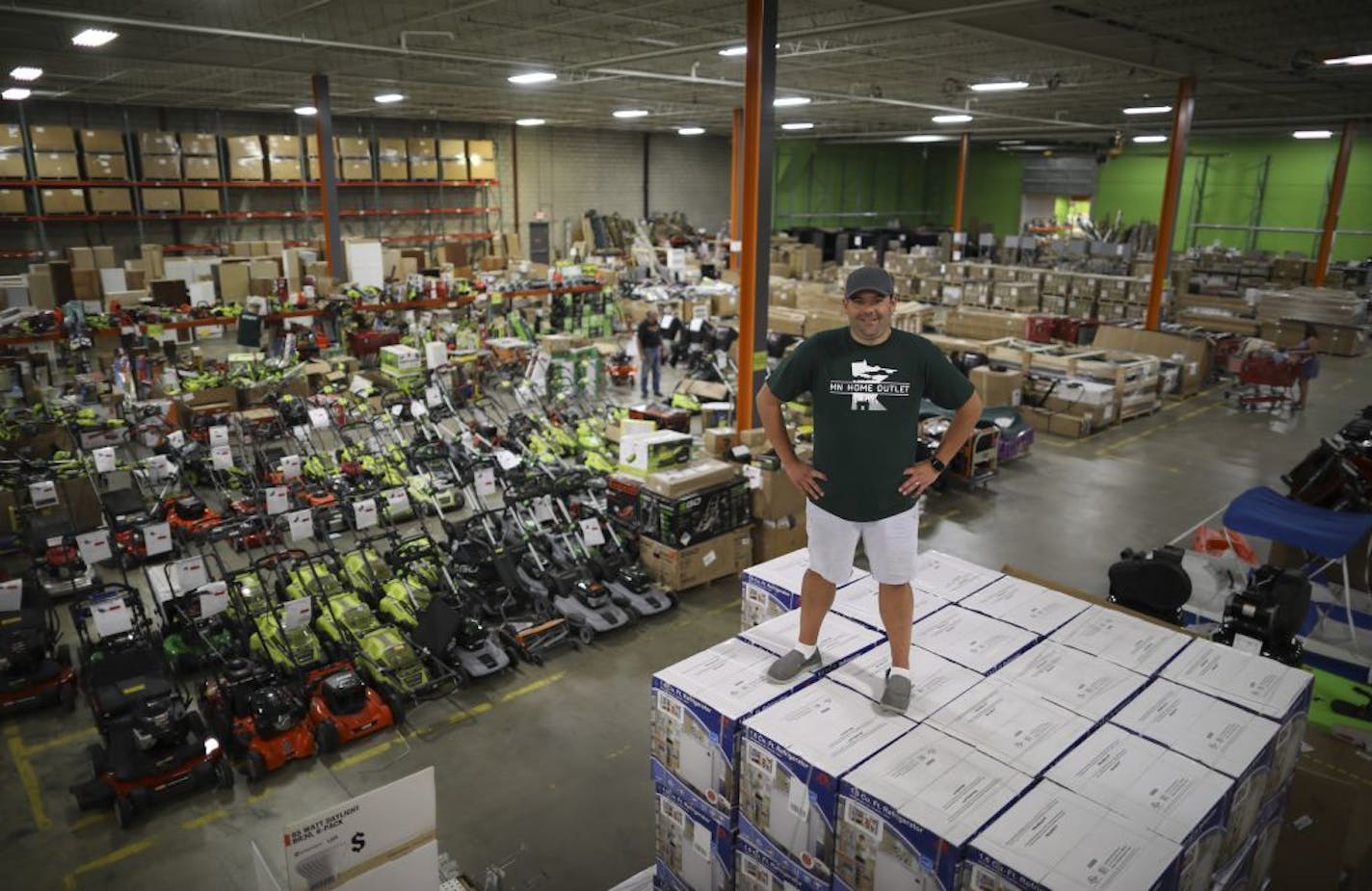 MN Home Outlet owner Jimmy Busika photographed atop a stack of dorm refrigerators in his vast Burnsville warehouse location.