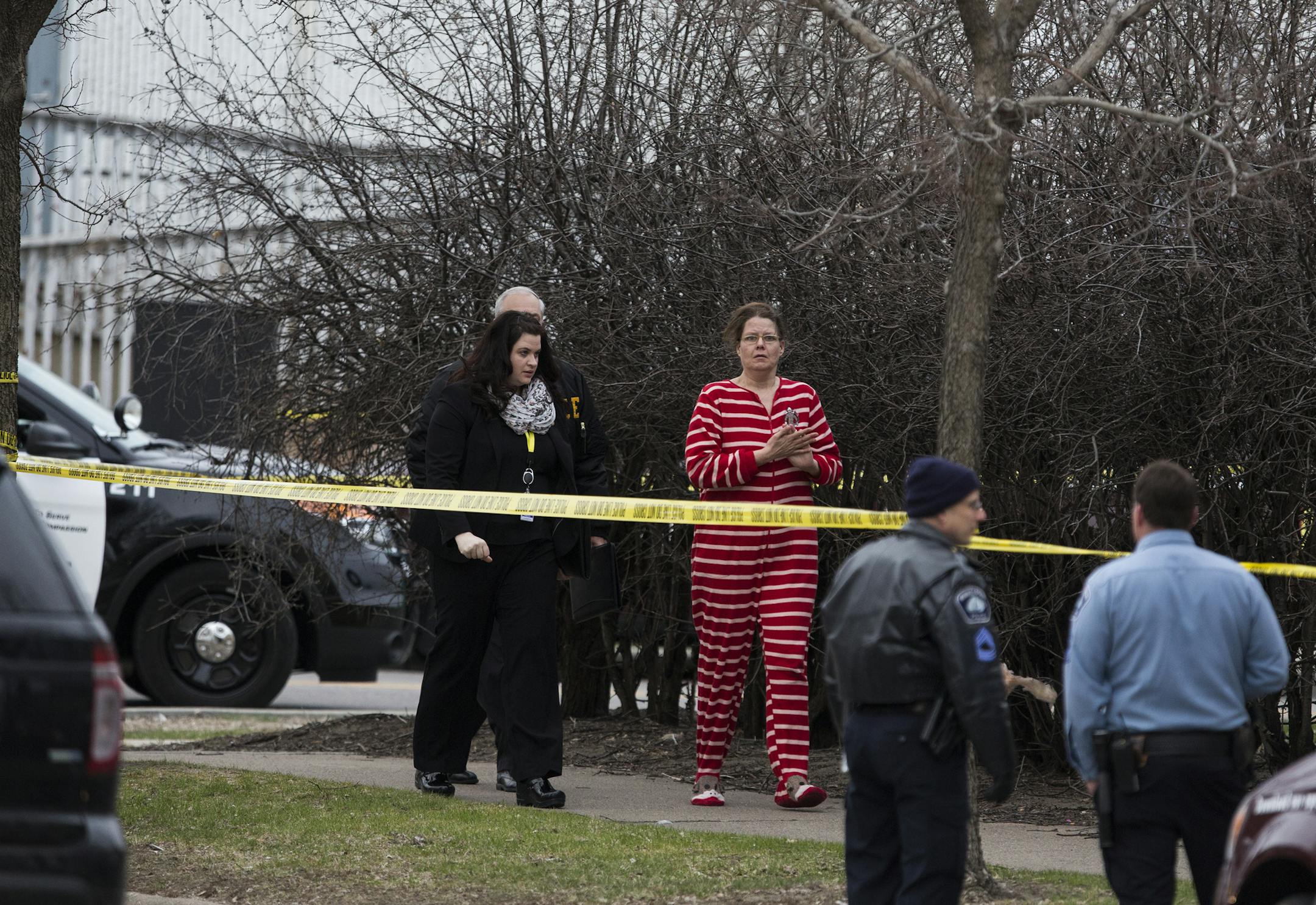 A woman in her pajamas is escorted by investigators back to the apartment building at the scene of an officer involved shooting in Minneapolis. ] (Leila Navidi/Star Tribune) leila.navidi@startribune.com BACKGROUND INFORMATION: Monday, April 4, 2016. A Minneapolis police officer was injured and a civilian was shot before dawn Monday during a call about a man with a knife at an apartment on the 2100 block of Minnehaha Avenue S. in Minneapolis.