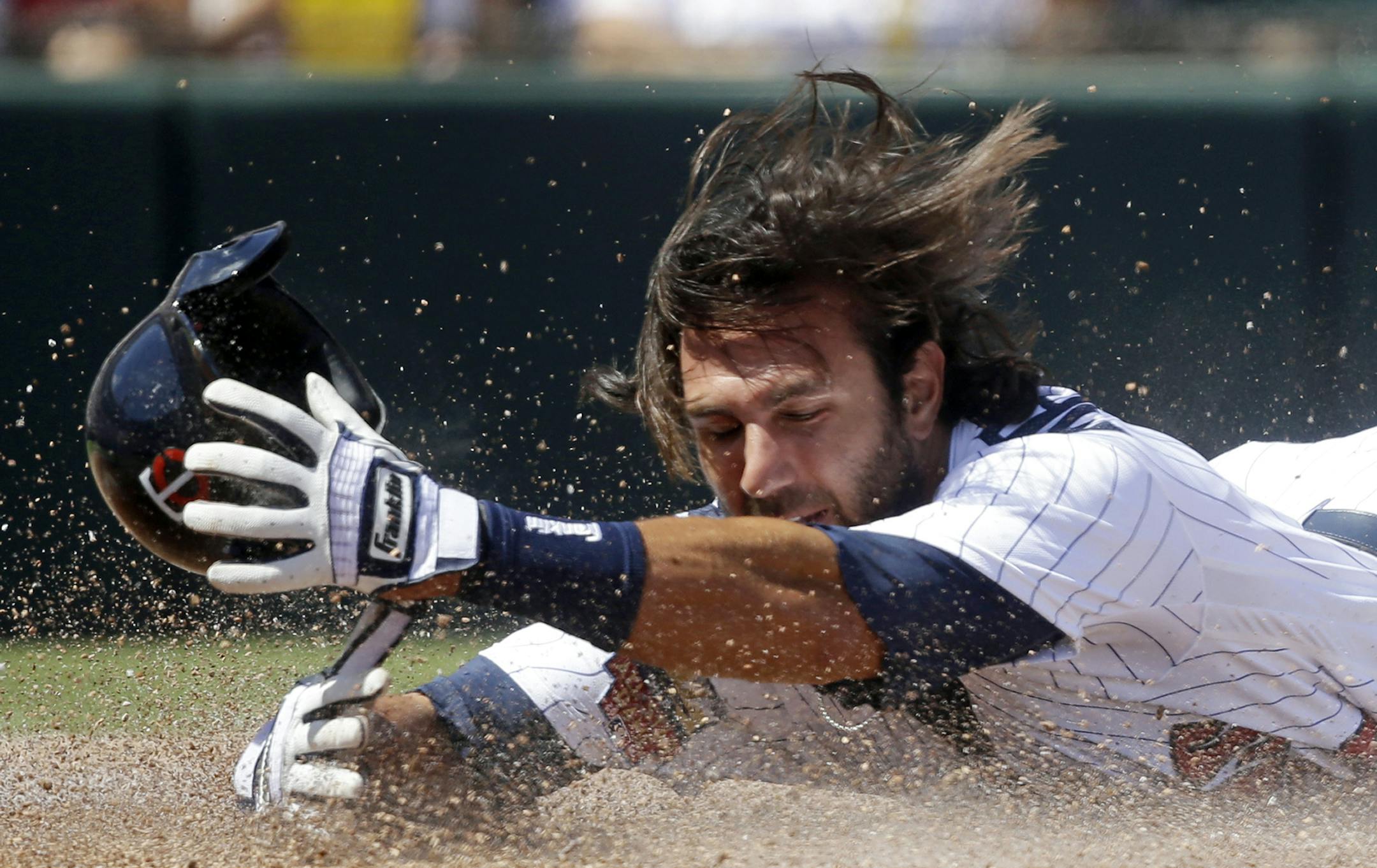 Twins center fielder Darin Mastroianni tried to catch his batting helmet as he reaches the plate ahead of the throw on a line drive by Joe Mauer in the first inning of an exhibition baseball game against the Philadelphia Phillies in Fort Myers, Fla., on Sunday.