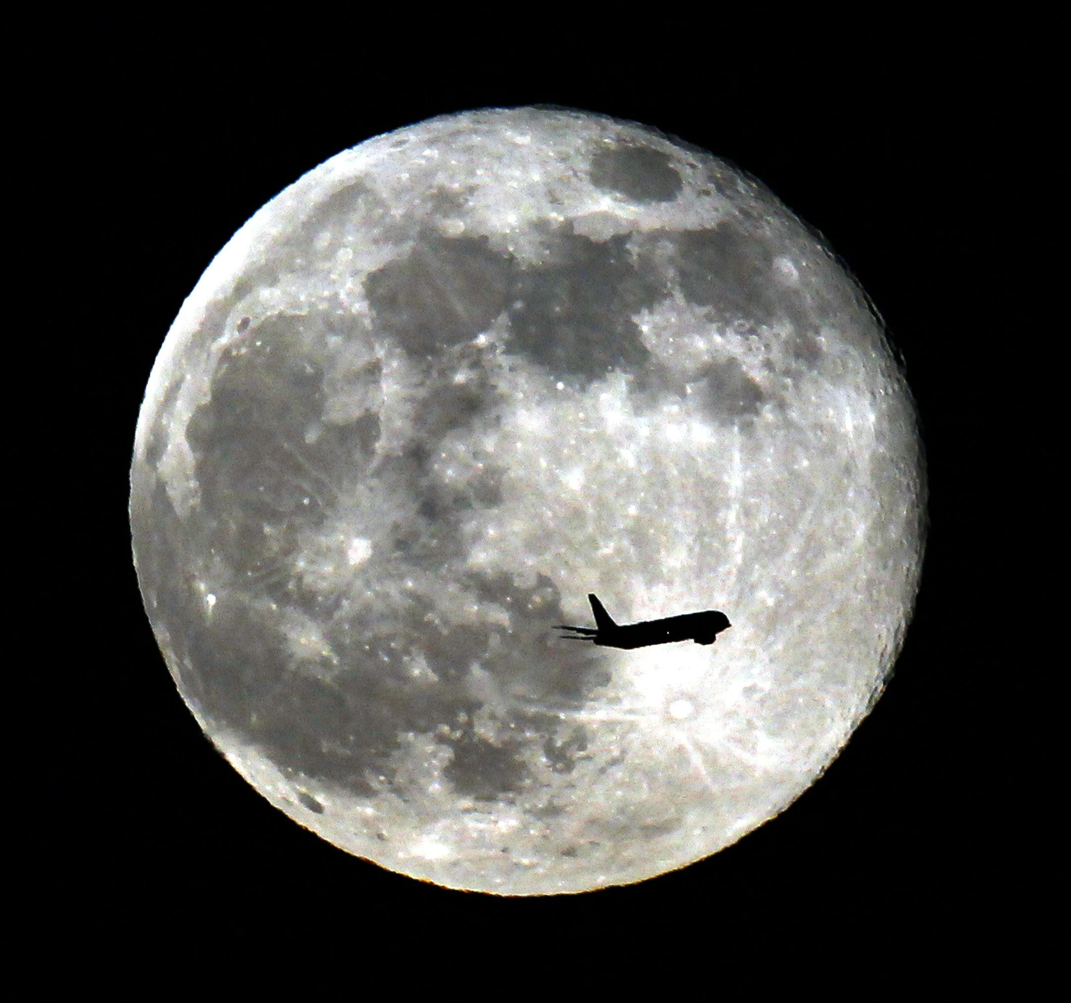 A jet plane passes in front of the supper full moon Sunday night in Monterey Park, Calif. June 23, 2013. Stargazers are still abuzz over the biggest and brightest full moon of the year, which graced the skies over the weekend. (AP Photo/Nick Ut)
