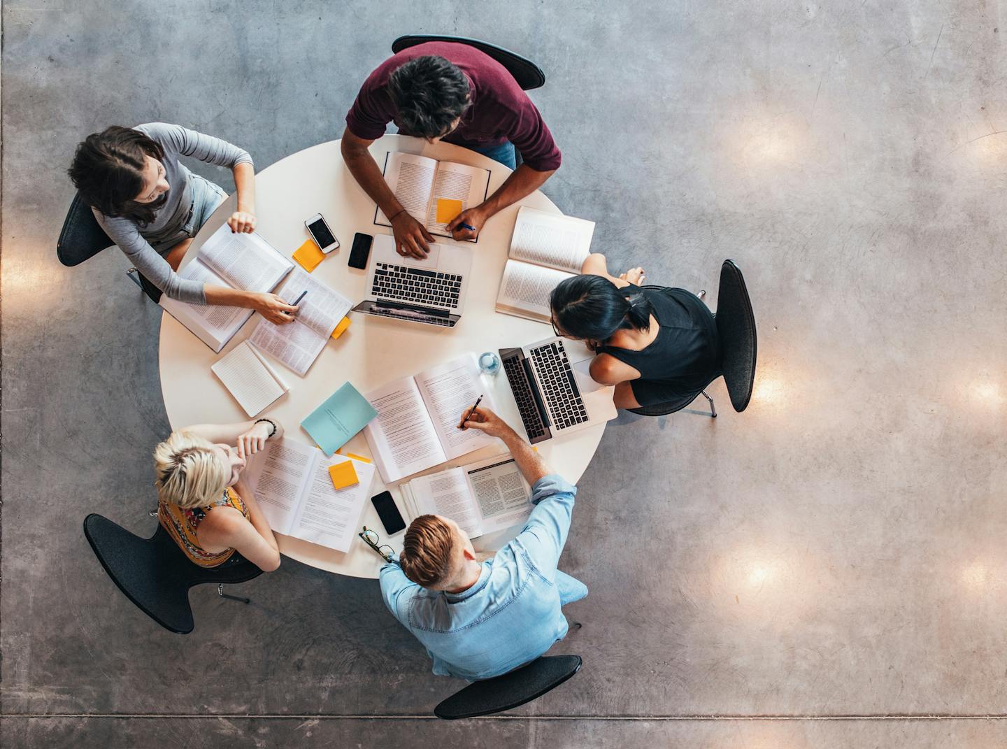 Top view of group of students sitting together at table. University students doing group study.