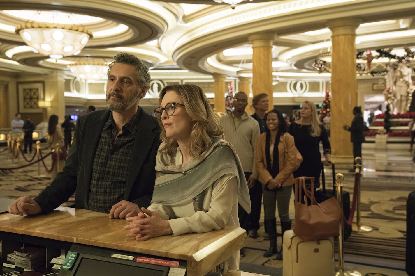 This image released by A24 shows John Torturro and Julianne Moore in a scene from "Gloria Bell." Everyone is vanishing around Julianne Moore's title character in Sebastian Lelio's "Gloria Bell." The disappearances don&#x2019;t come with blood-curdling shrieks or thundering score cues, but with the humdrum ebb of middle age. People just move away or recede from view. (A24 via AP)