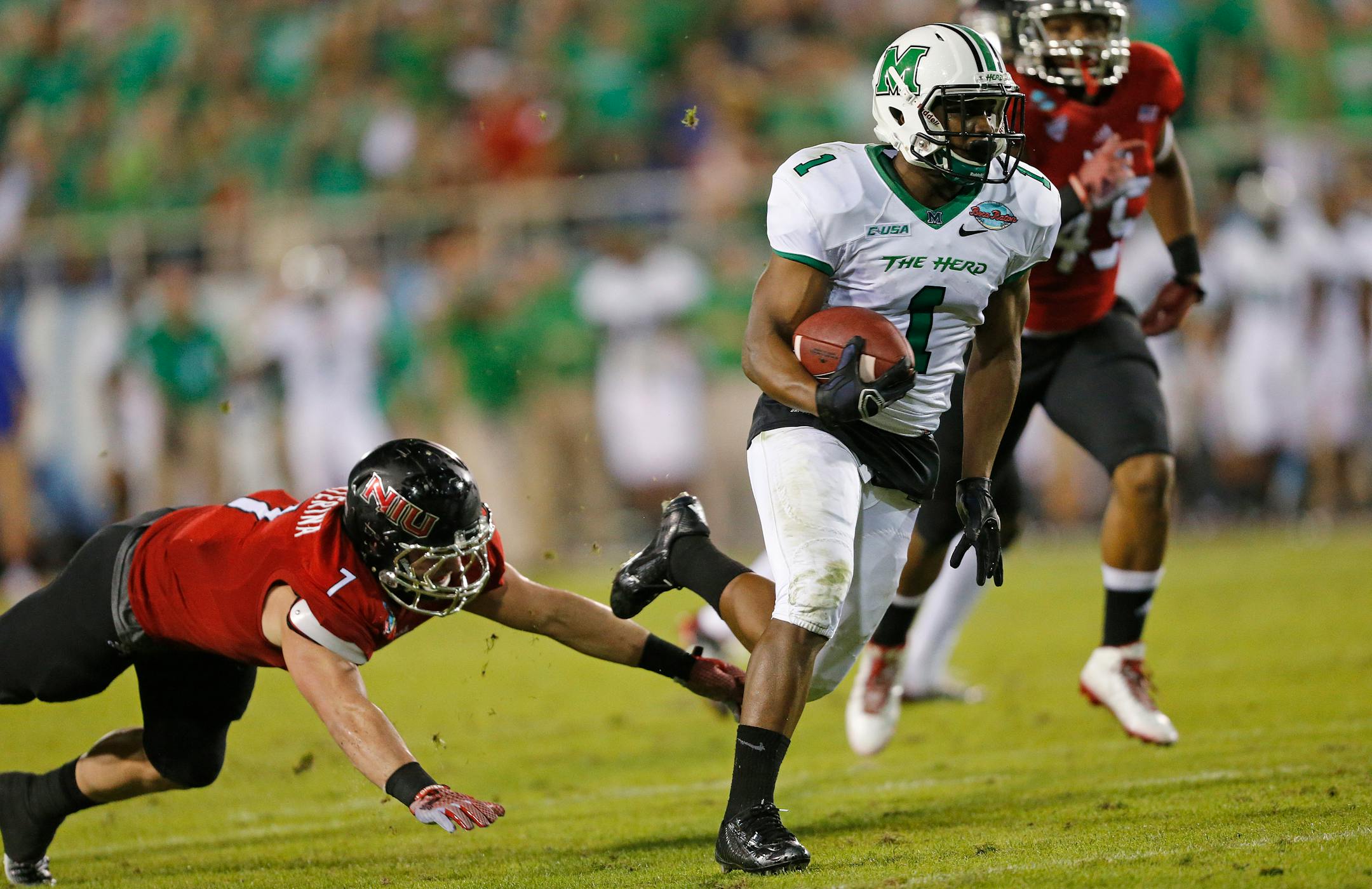 Marshall�s Tommy Shuler (1) eludes the tackle of Northern Illinois� Michael Santacaterina (7) during second half action of the Boca Raton Bowl NCAA college football game on Tuesday, Dec. 23, 2014, at FAU Stadium in Boca Raton, Fla. Marshall defeated Northern Illinois 52-23. (AP Photo/Joel Auerbach)
