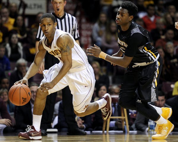 Minnesota guard Deandre Mathieu, left, dribbles against Maryland-Baltimore County guard Jourdan Grant (5) during the second half of an NCAA college ba