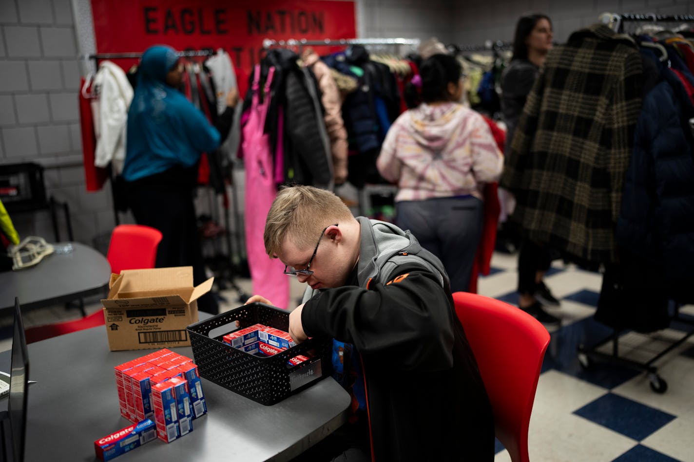 Eleventh-grader Christopher Rogers restocks toothpaste at the Eagle Nation Station, a free pantry offering food, school supplies, personal hygiene items, clothing and even household items like laundry detergent to students in need, at Eden Prairie High School on Tuesday, Dec. 19, 2023 in Eden Prairie, Minn. ] RENEE JONES SCHNEIDER • renee.jones@startribune.com