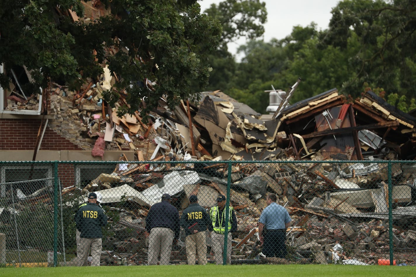 NTSB officials and Minneapolis police view the rubble at Minnehaha Academy.