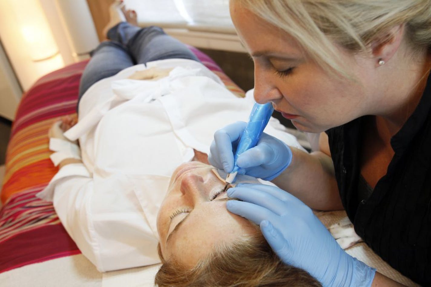 Angie Scott tattoos eyeliner on Joani Donovan, at Faces in Lambertville, Ohio.