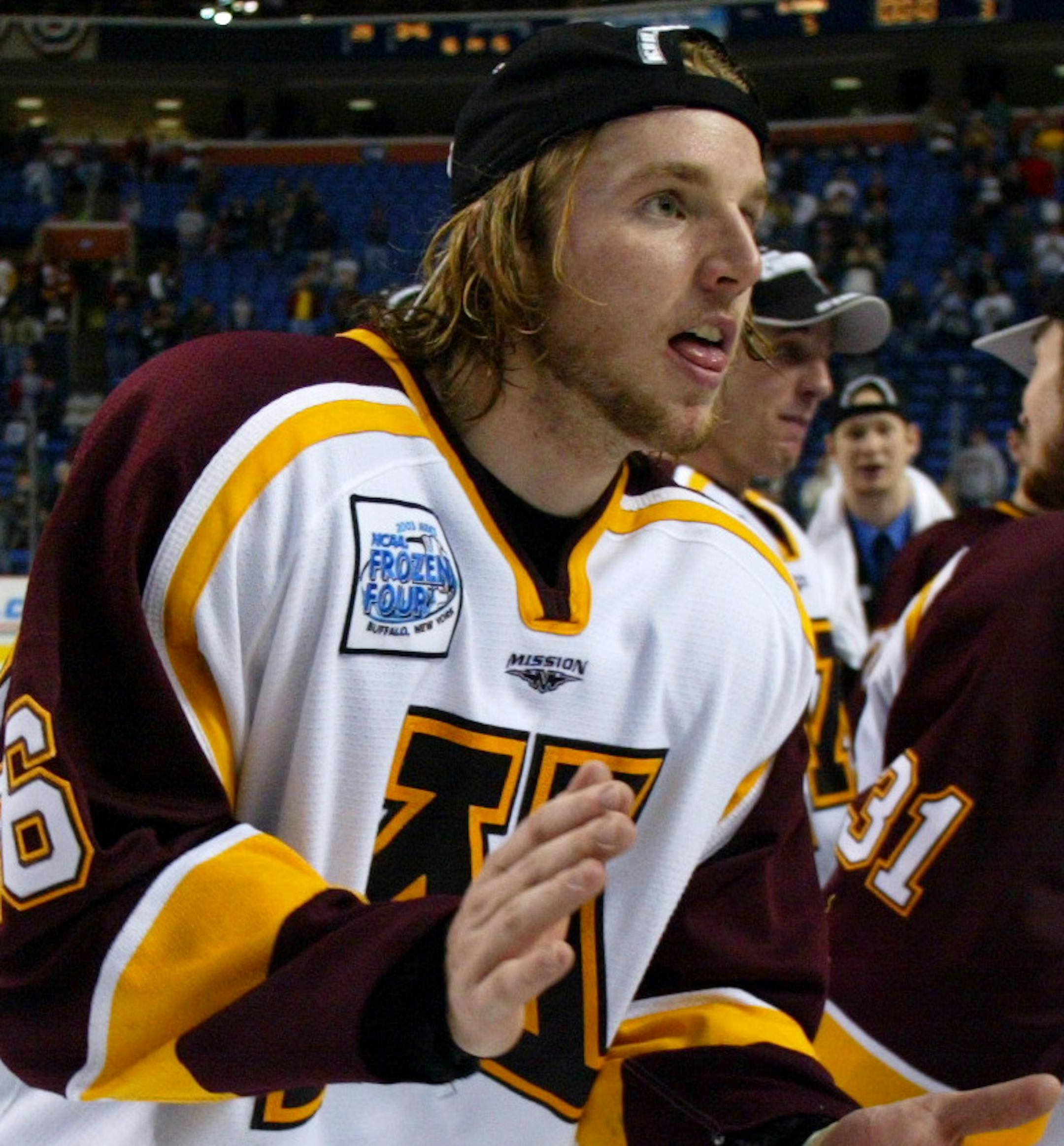Buffalo, New York, Saturday, 4/12/2003. Frozen Four Championship game between Minnesota and the University of New Hampshire. (center) Minnesota's Thomas Vanek skated to get his national medal as his teammates celebrated after beating New Hampshire.