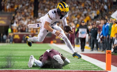 Michigan quarterback J.J. McCarthy dives over Minnesota defensive back Tariq Watson to score a touchdown in their October 2023 game at Huntington Bank