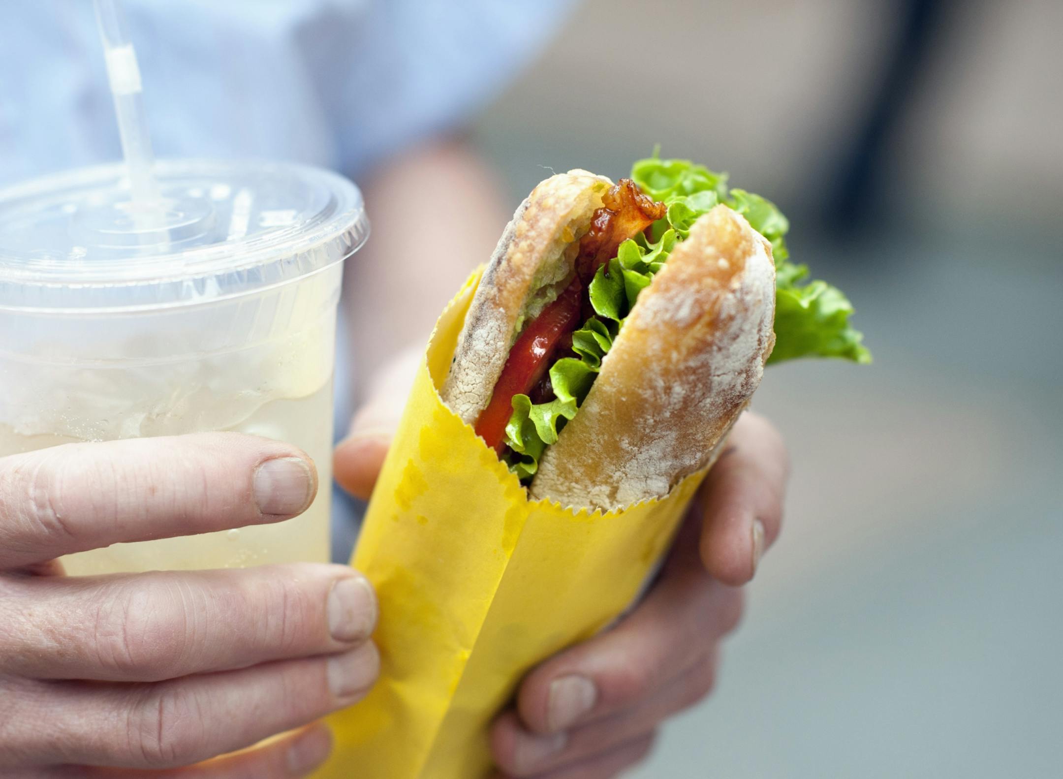 A Dandelion Kitchen customer holds a homemade basil-lime soda and a B.L.T. The Dandelion Kitchen was parked Thursday outside the IDS Tower on Nicollet Mall. The B.L.T. is maple-glazed Minnesota bacon, lettuce, local tomato and avocado for $6.75.