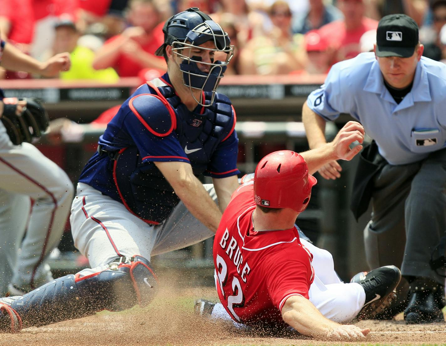 Minnesota Twins' catcher Joe Mauer tags out Cincinnati Reds' Jay Bruce (32) at home in the sixth inning of a baseball game, Sunday, June 24, 2012, in Cincinnati. Minnesota won 4-3. Home plate umpire Mike Muchlinski watches the play.