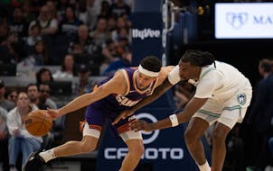 Suns guard Devin Booker (1) steals the ball from Timberwolves center Naz Reid (11) in the fourth quarter in Game 1 on Saturday. Despite the 25-point l