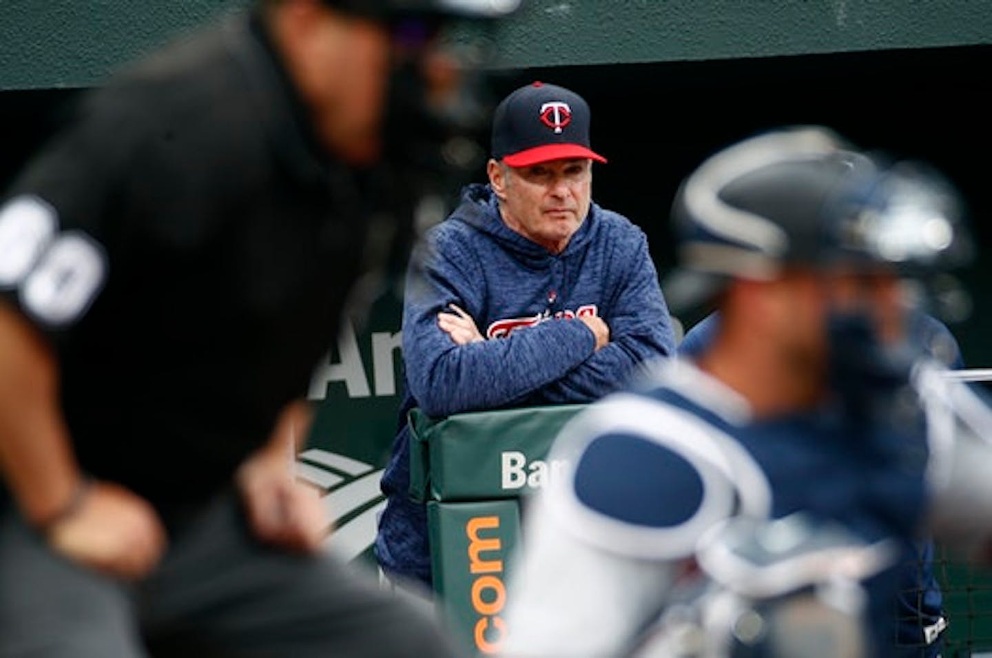 Minnesota Twins manager Paul Molitor is seen past home plate umpire Marty Foster, front left, and Twins catcher Mitch Garver as he watches the seventh inning of a baseball game against the Baltimore Orioles, Sunday, April 1, 2018, in Baltimore.