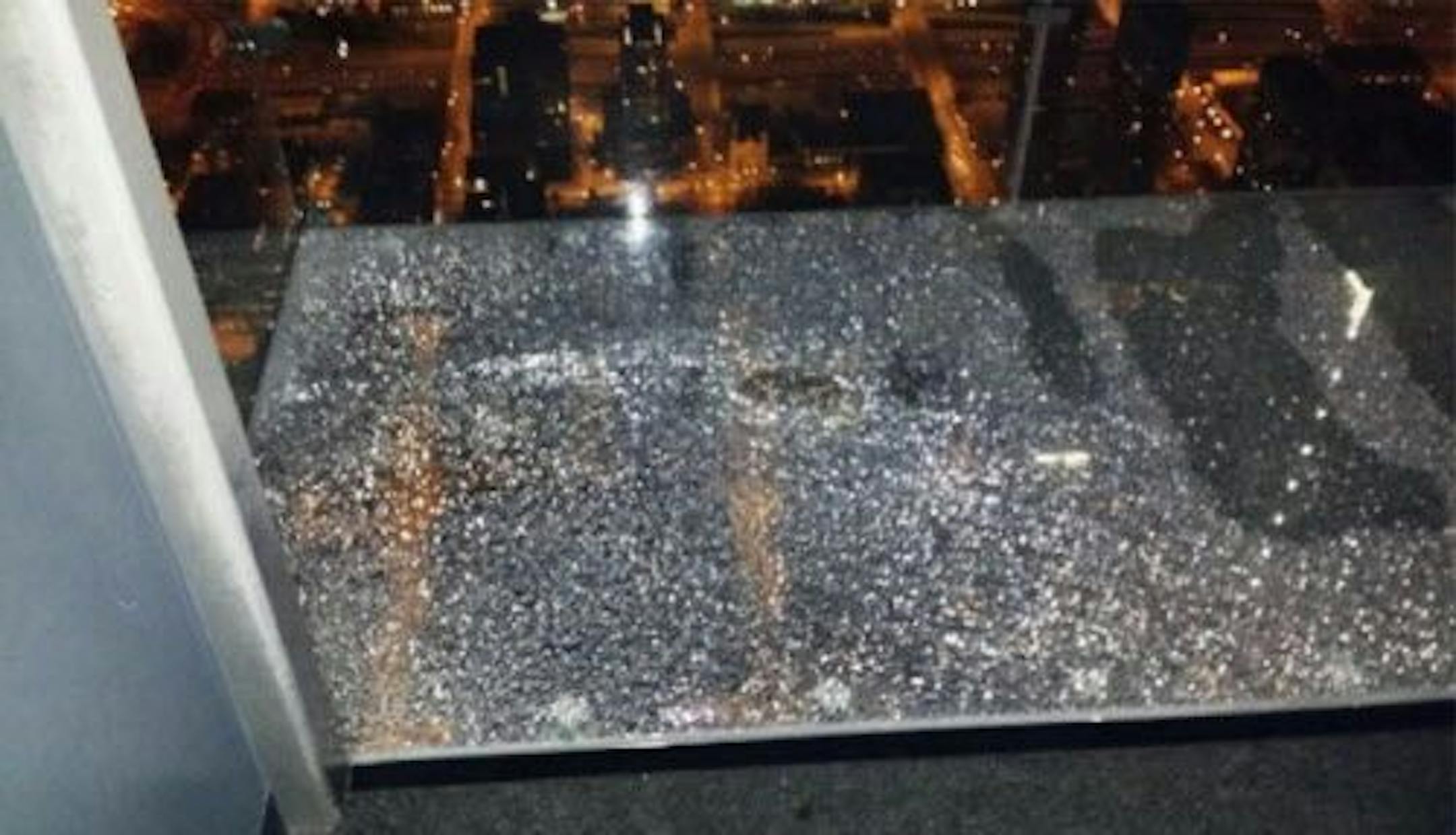 This Wednesday, May 28, 2014 photo provided by Alejandro Galibay shows the cracked coating of one of the glass bay of The Ledge, a popular tourist attraction on the 103rd story of the Willis Tower in Chicago.