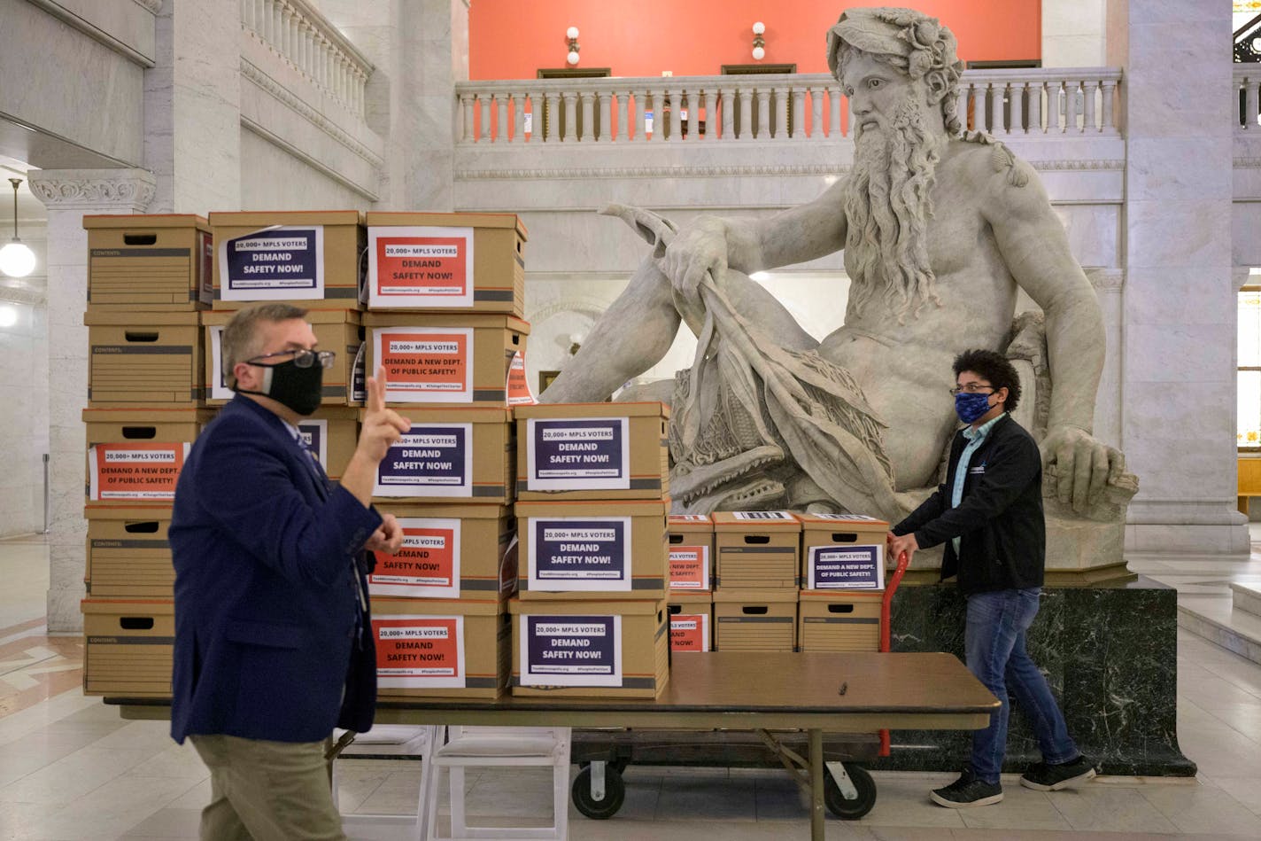 Minneapolis City Clerk Casey Carl, left, and election administrator Jon Martin worked to move 30 boxes with more than 20,000 signed petitions after community activists delivered them to City Hall.