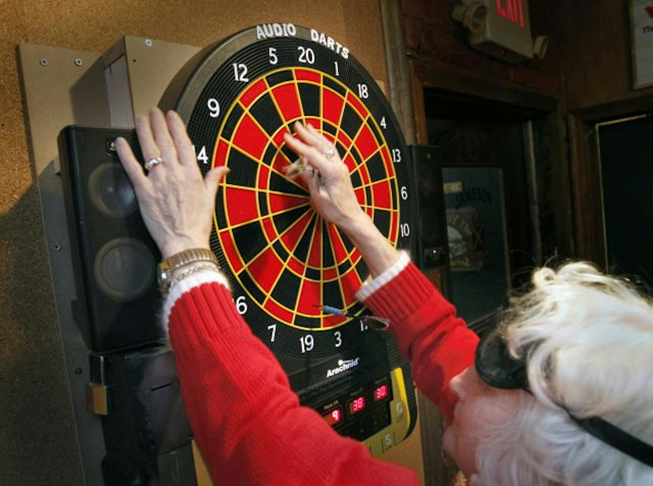 Diane Ruffcorn feels for her darts after a turn at the audio board. About half of the players on the league's six teams are legally blind; all wear blindfolds.