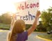 Megan Smith, a junior, holds up a sign a for new students as they arrive for freshman orientation at Visitation High School in Mendota Heights, Minn.,