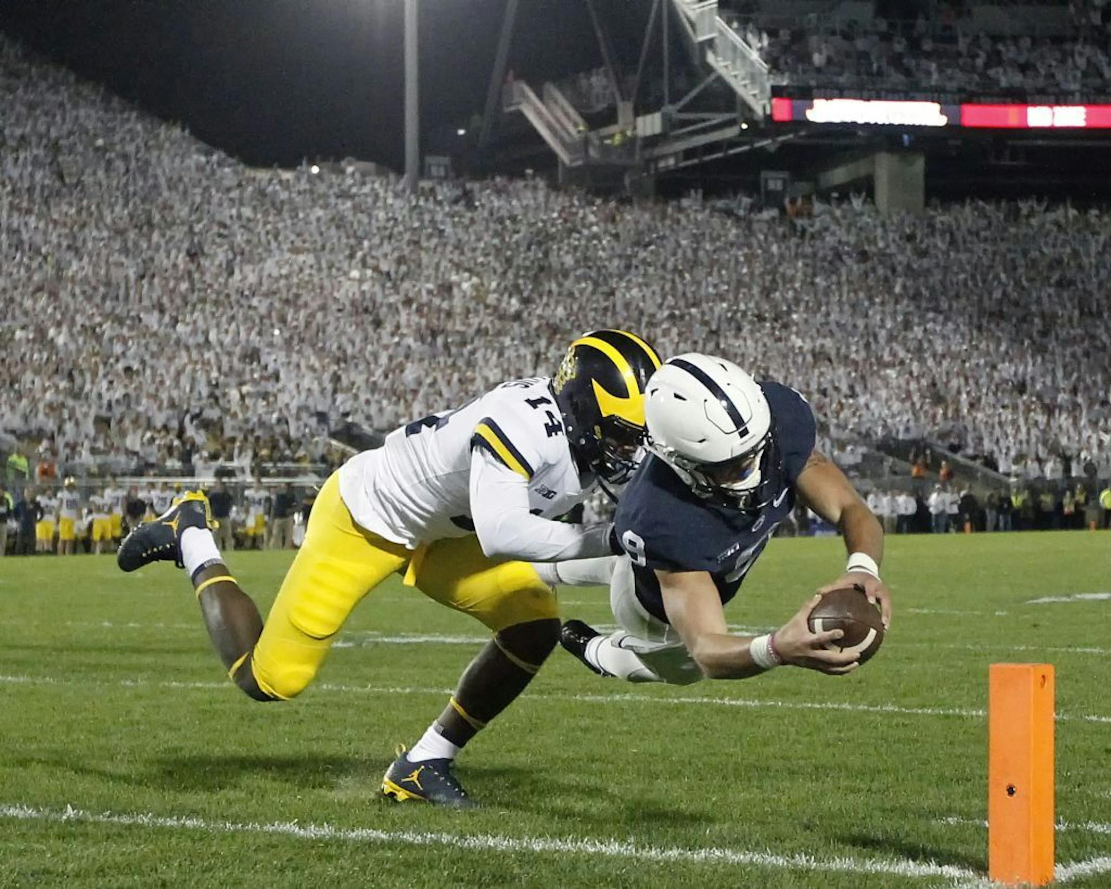 Penn State quarterback Trace McSorley (9) dives in for a touchdown as Michigan's Josh Metellus (14) defends during the second half of an NCAA college football game in State College, Pa., Saturday, Oct. 21, 2017. Penn State won 42-13.