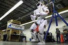 In this May 2, 2016 photo, researchers watch a six-foot-tall, 300-pound Valkyrie robot walk slowly at University of Massachusetts-Lowell's robotics ce