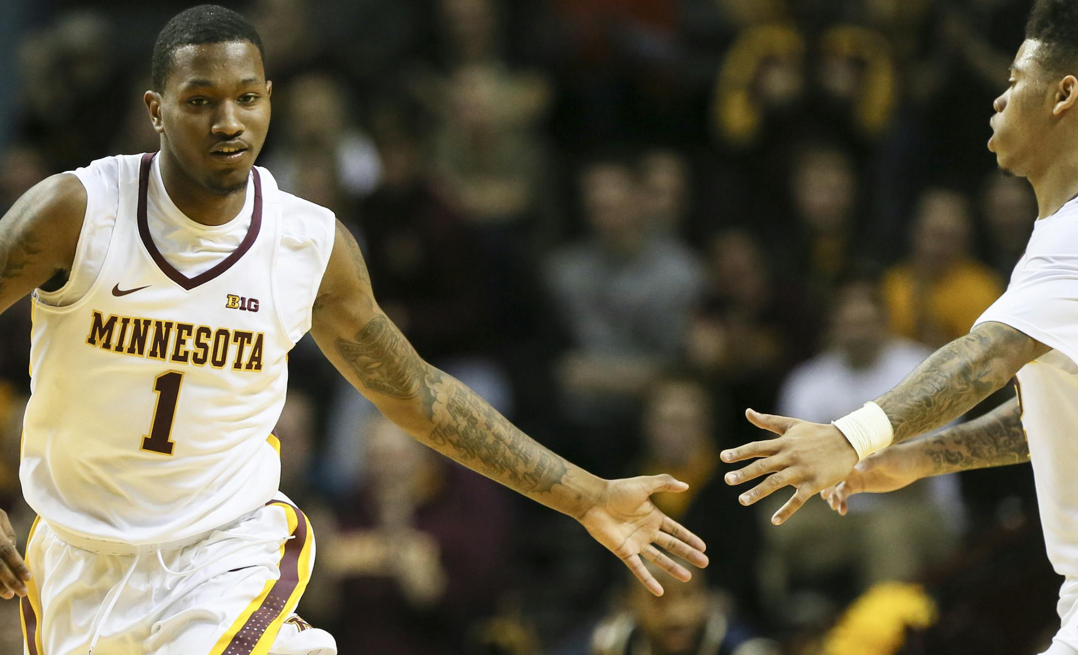 Minnesota's Dupree McBrayer (1) high-fived teammate Nate Mason after scoring during the first half.