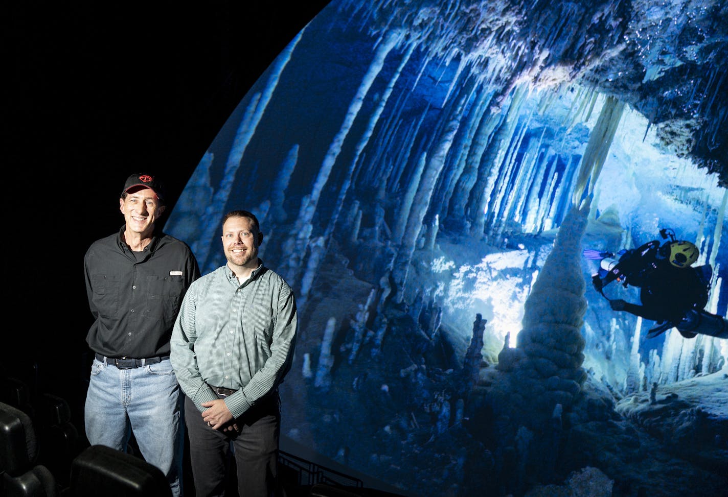 Founding director of the Omnitheater Mike Day and Omnitheater technical director Chris Demko posed for a photo in from of the new digital Omnitheater with the production Ancient Caves on the screen at the Science Museum of Minnesota in St. Paul, Minn., on Monday, October 7, 2019. We we able to pause the film to get this shot, something the previous film projector could not do. ] RENEE JONES SCHNEIDER &#xa5; renee.jones@startribune.com