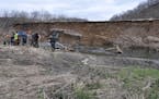 A group of state officials and Driftless Area trout stream conservations inspect slope damage in the Rushford area caused by spring flooding. Washouts