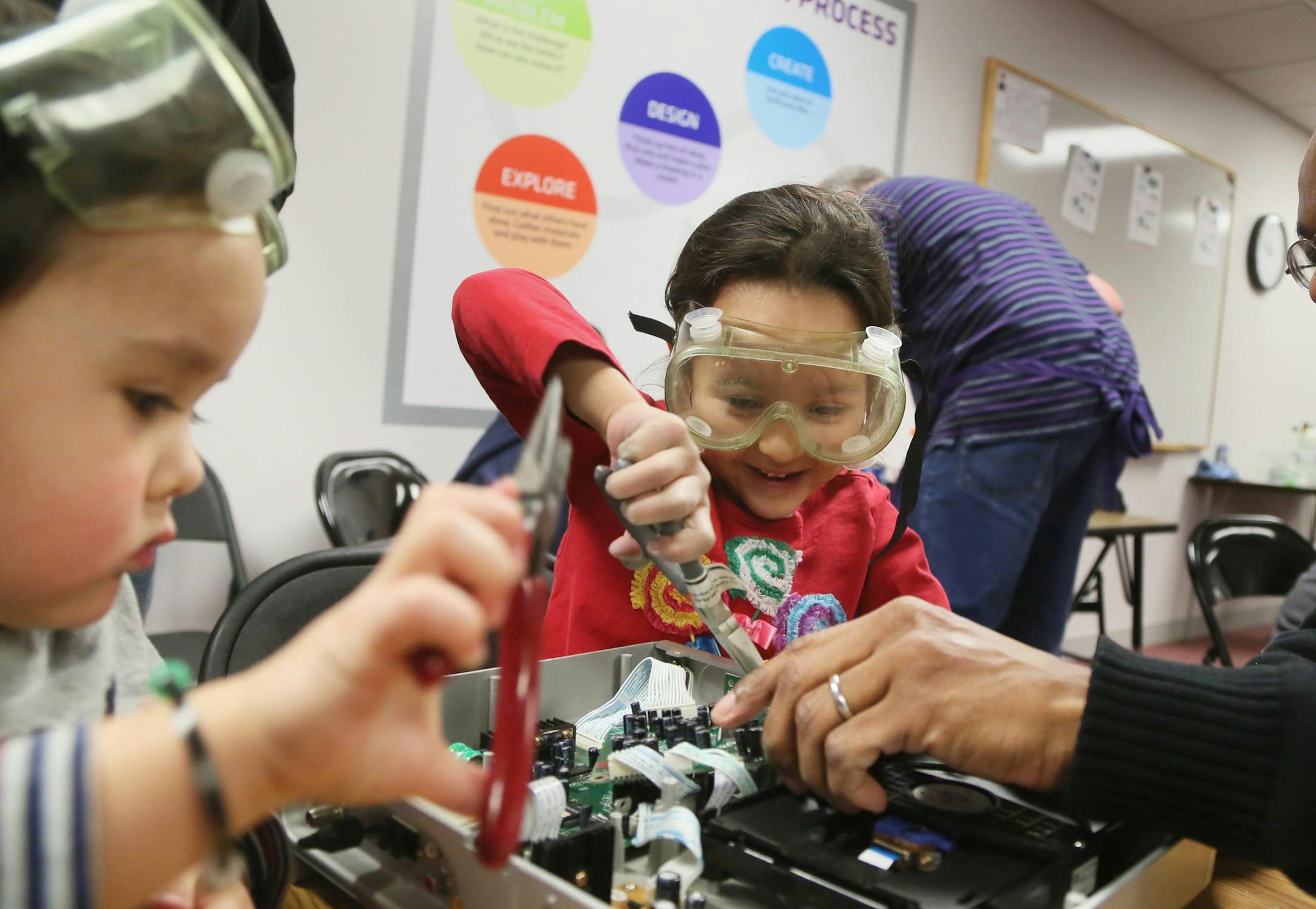 The Works Museum exploded with activity during the annual celebration of National Engineers Week Saturday, Feb. 28, 2015, in Bloomington, MN. Here, Caroline Fairbrother, 6, middle, and her brother Lucas, 3, did some reverse engineering on a DVD player with the help of volunteer Ted Williams, an engineer for Xcel Energy, right. Caroline and Lucas used pliers to remove capacitors and circuits from the player. "This whole entire city," Caroline said, referring to the numerous parts in the player, "