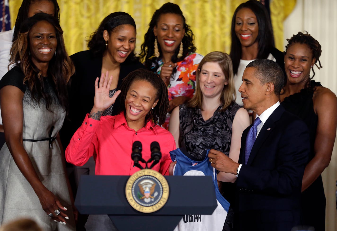 President Barack Obama, right, is presented with a Lynx team basketball jersey by Seimone Augustus, center, as he honors the WNBA Champion Minnesota Lynx, Tuesday, Sept. 18, 2012, in a ceremony in the East Room of the White House in Washington. (AP Photo/Pablo Martinez Monsivais)