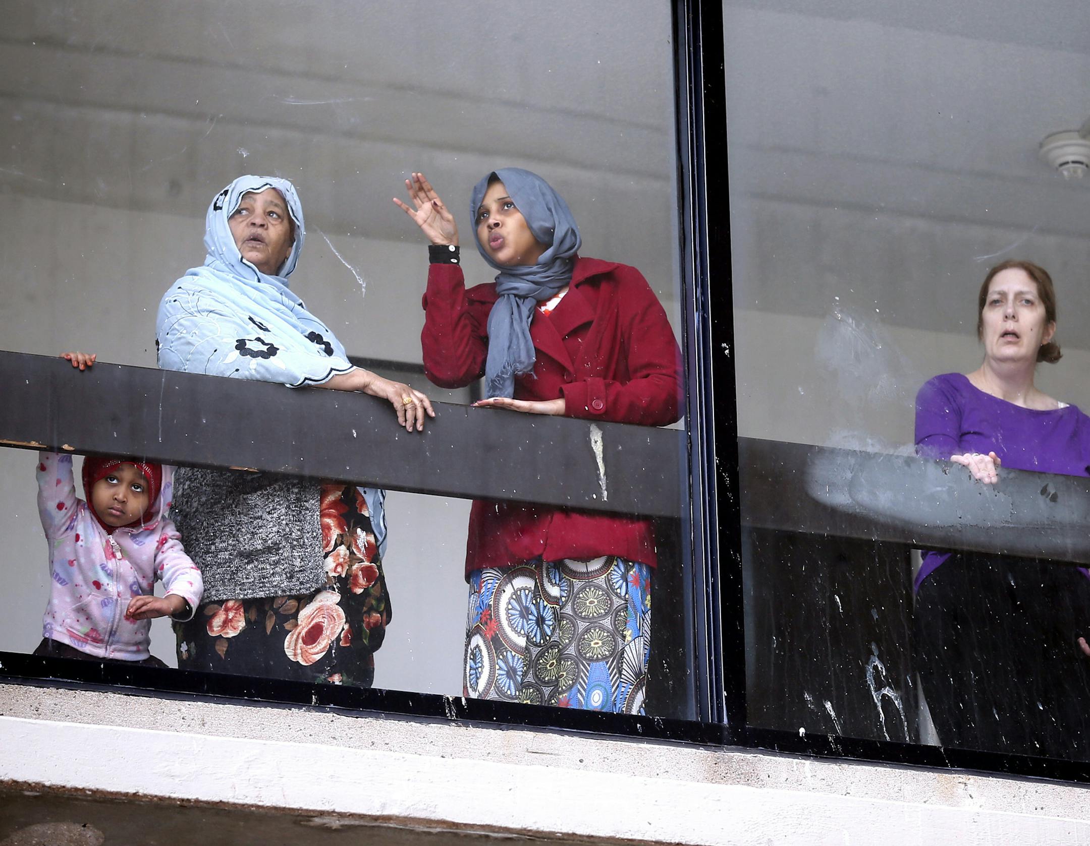 A group people looked through a window as fire fighters battled a 3-alarm fire an explosion at 514 Cedar Avenue January 01, 2014 in Minneapolis ,MN. Thirteen people were injured, six critically, early Wednesday morning after an explosion caused a major fire at a grocery store and apartment building in the bustling Cedar-Riverside neighborhood ] JERRY HOLT ‚Ä¢ jerry.holt@startribune.com