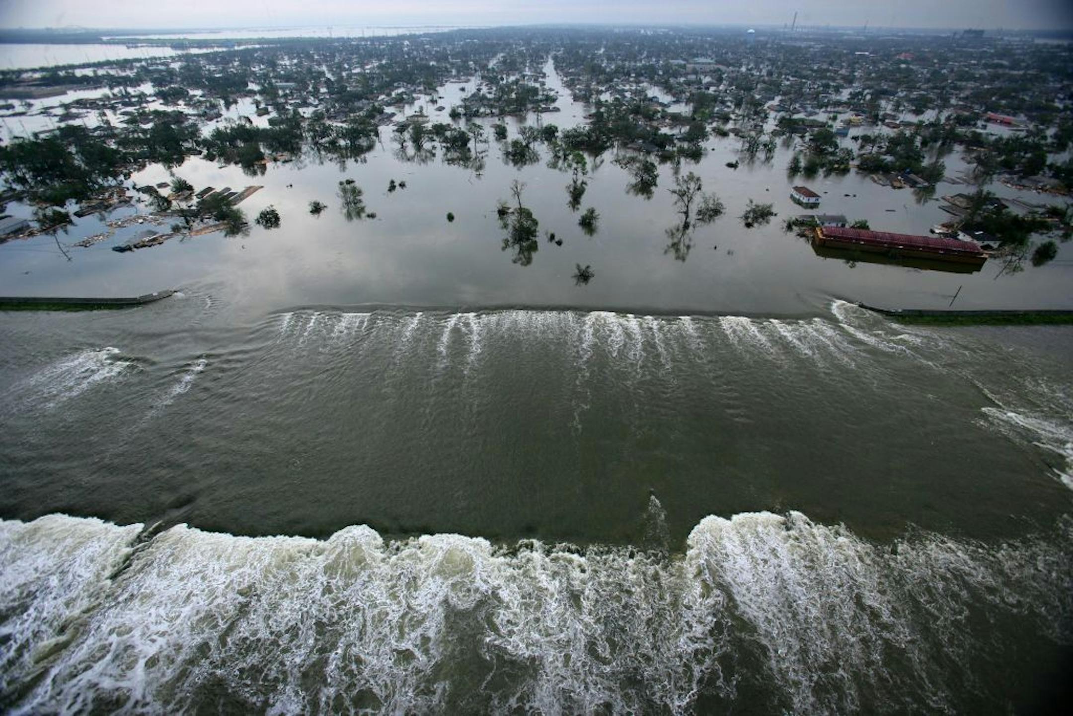 In this Aug. 30, 2005 file photo, flood waters from Hurricane Katrina pour through a levee near downtown New Orleans, La.