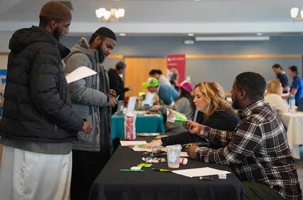 Christina Kitt and Henok Fanta with Washington County speak to potential employees during a job fair inside the Maplewood YMCA Community Center on Tue