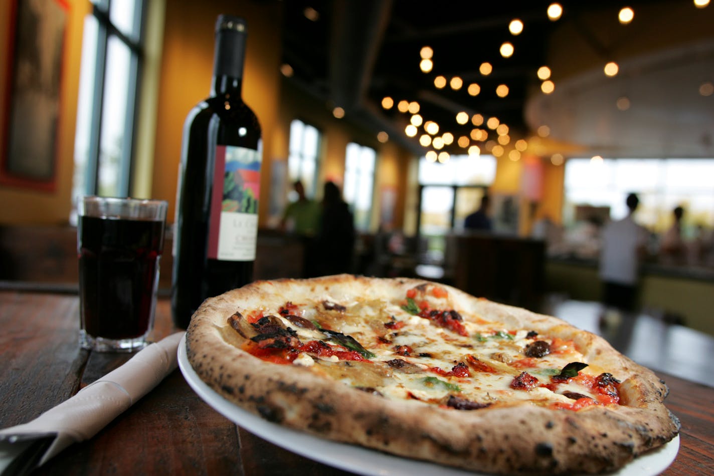 Punch's Borgata pizza, topped with sun-dried tomato, goat cheese, eggplant, saracene olive and basil, is baked in a wood burning oven fired to 800 degrees. The pizzas at Punch cook in 90 seconds.