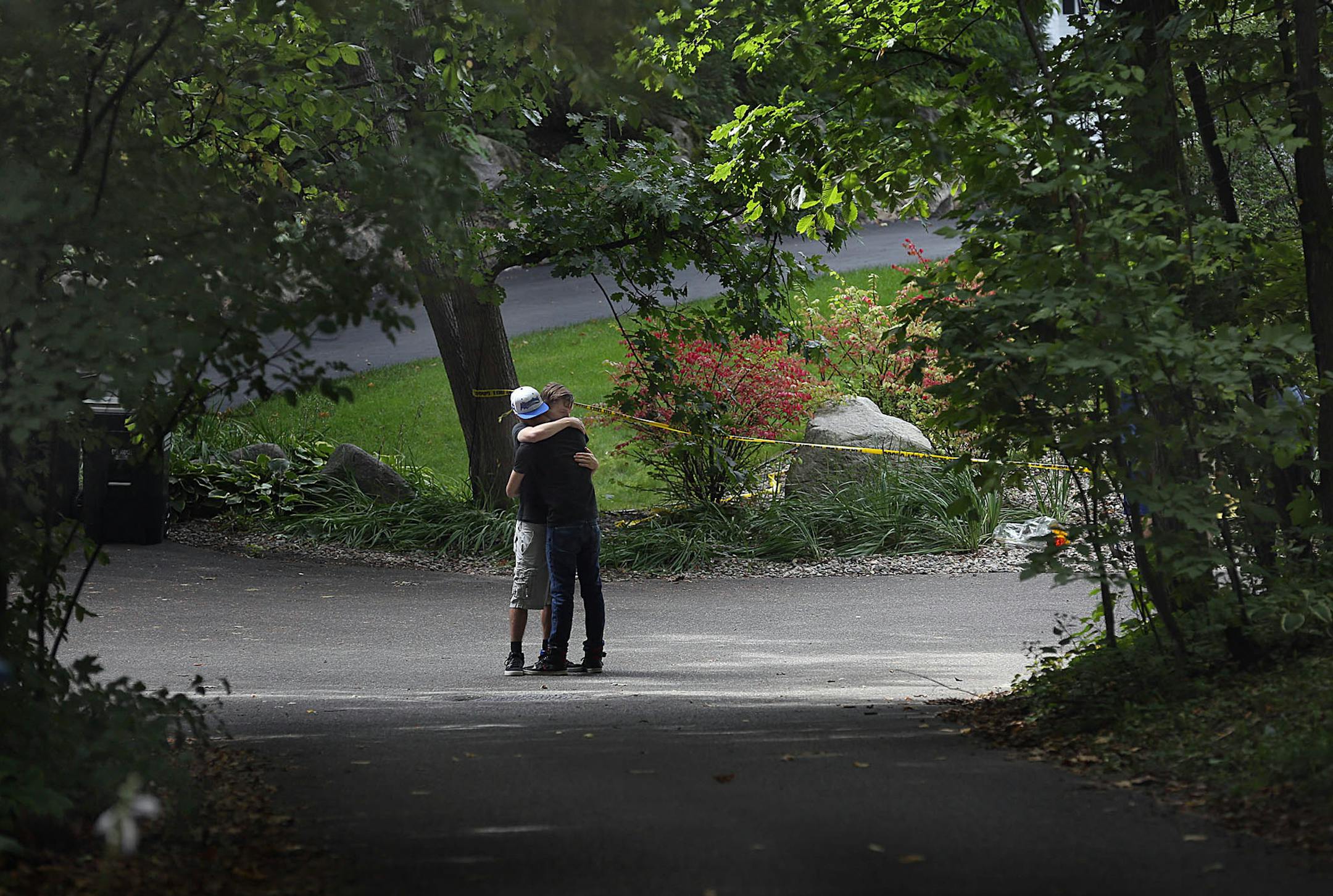 Two Minnetonka High classmates of the victims hugged each other at the home in Greenwood where a family was found dead.