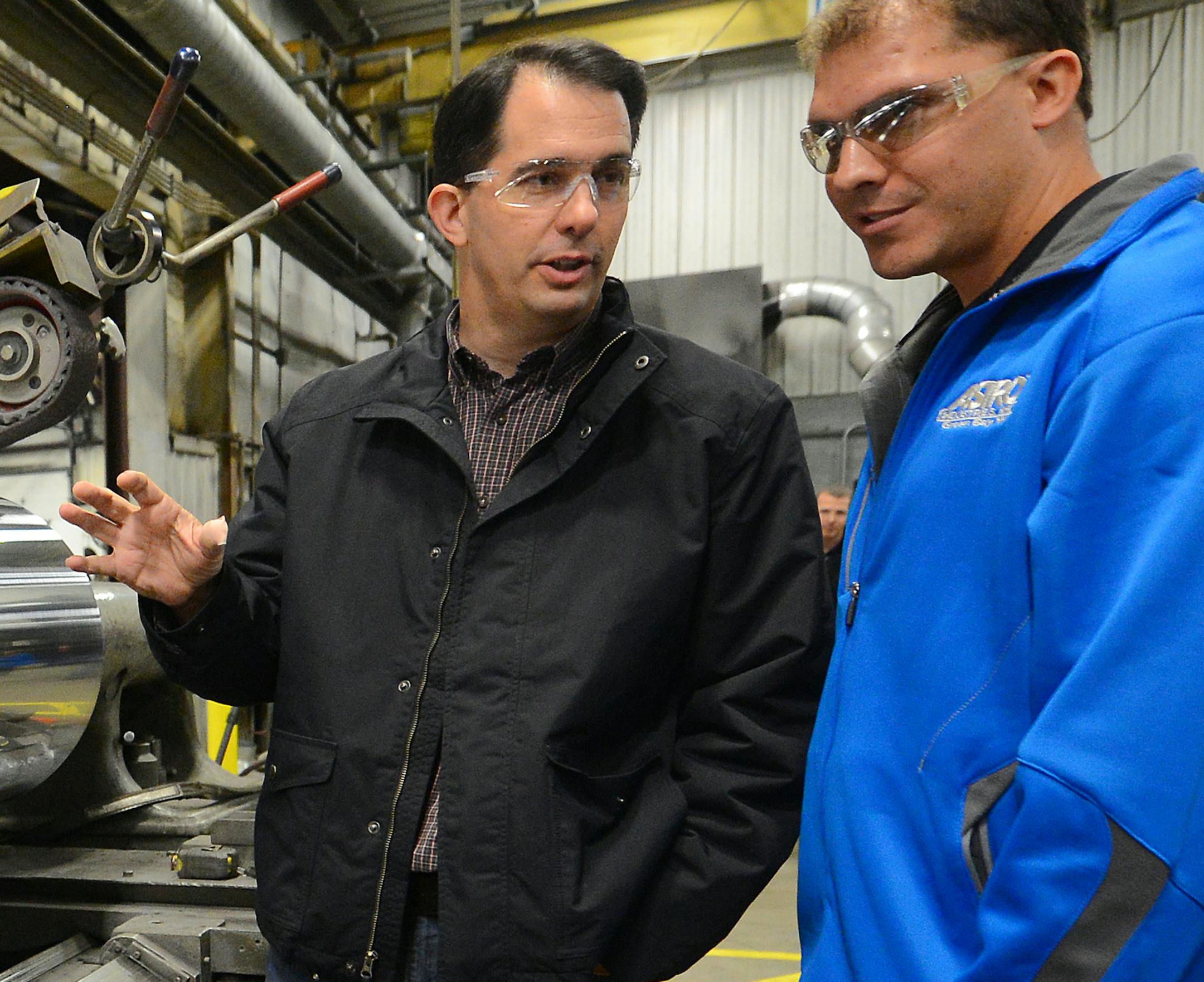 Wisconsin Gov. Scott Walker, left, asks Eric Guns a few questions about the nickel plating process during a campaign visit to Astro Industries in Ashwaubenon, Thursday, Oct. 30, 2014. (AP Photo/The Green Bay Press-Gazette, Jim Matthews) NO SALES ORG XMIT: MIN2014110115325323