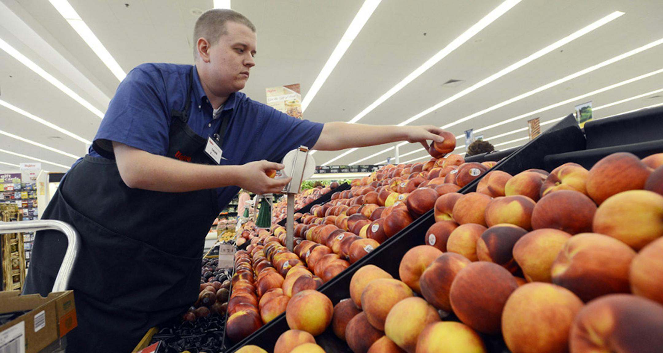 FILE-In this Monday, Aug 27, 2012, file photo, Caleb Tollefson stocks a display of nectarines and peaches at a Hy-Vee grocery store in Sioux Falls, S.D. (AP Photo/Argus Leader, Elisha Page) ORG XMIT: NYBZ134