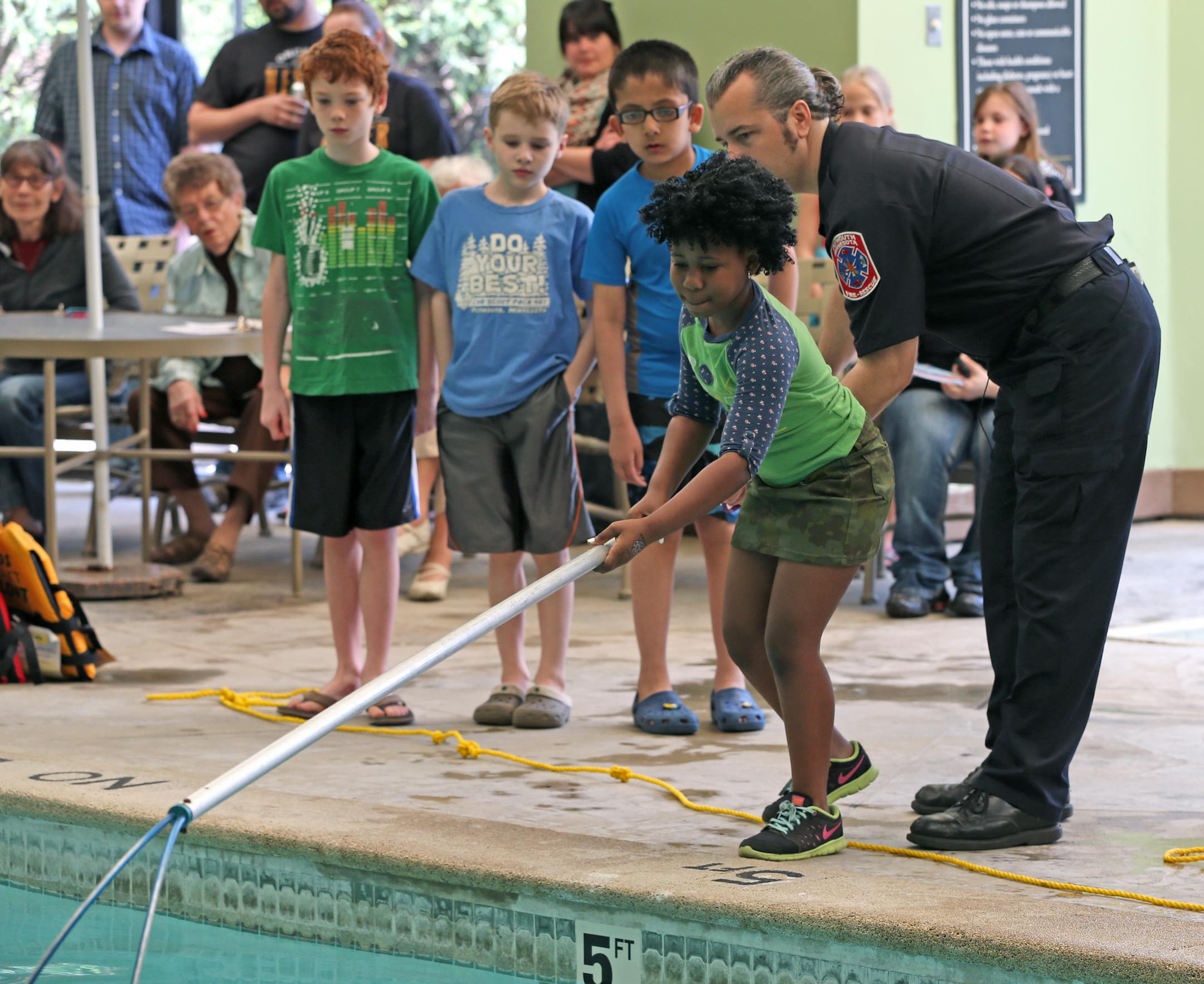 Samantha Richardson, age-8, sister of Benedict Richardson, was helped by Plymouth fireman Paul Larson as she learned how to use a pole to rescue a drowning person during a free water safety demonstration to promote drowning prevention and to teach emergency response. The demonstration was open to residents of the Plymouth Square building on 5/17/14. MN Water Safety Coalition with help from the Hennepin Sheriff Dept., Plymouth Fire, YMCA and Abby's Hope held the seminar. 16-year-old Benedict Rich