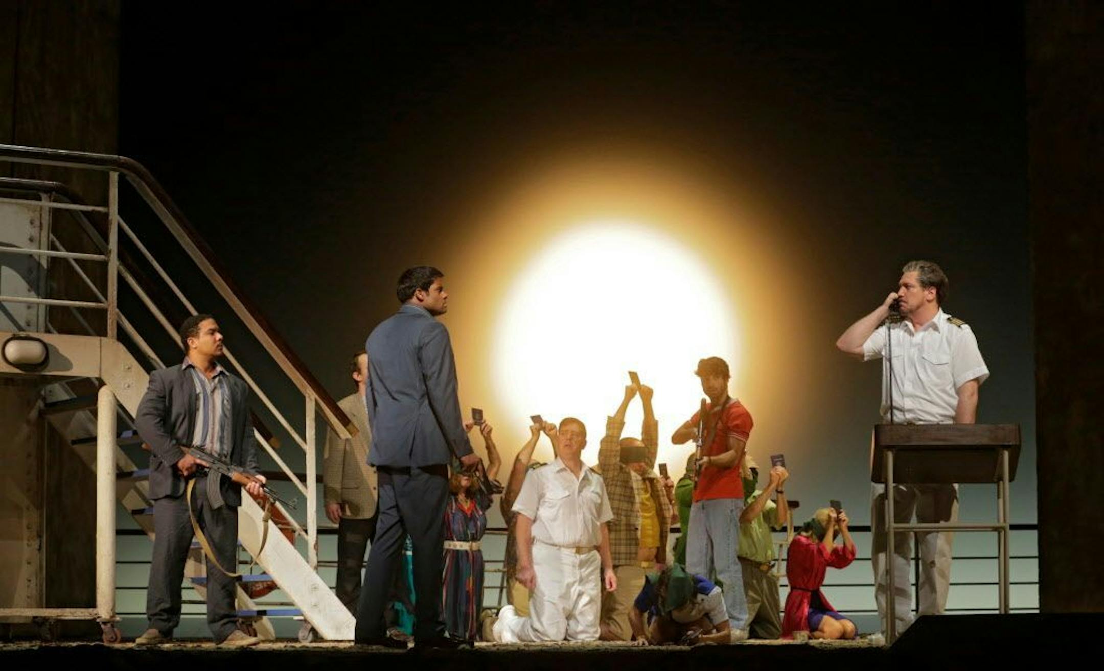 In this image released by the Metropolitan Opera, Aubrey Allicock as Mamoud, foreground from left, Sean Pannikar as Molqui, and Paulo Szot as the Captain, perform with the cast in "The Death of Klinghoffer," at the Metropolitan Opera in New York.