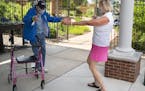 Victoria Conrad opens her arms to do a distant hug with her 99-year old father Howard Seitzer as they met for their first face-to-face visit since the