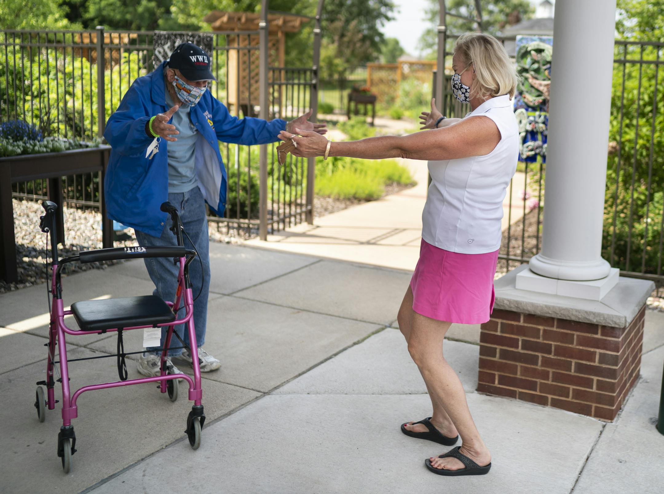 Victoria Conrad opens her arms to do a distant hug with her 99-year old father Howard Seitzer as they met for their first face-to-face visit since the COVID-19 pandemic closed off his senior living home to visitors in March at Oak Meadows Senior Living in Oakdale, Minn., on Thursday, June 18, 2020. (Renee Jones Schneider/Star Tribune via AP)