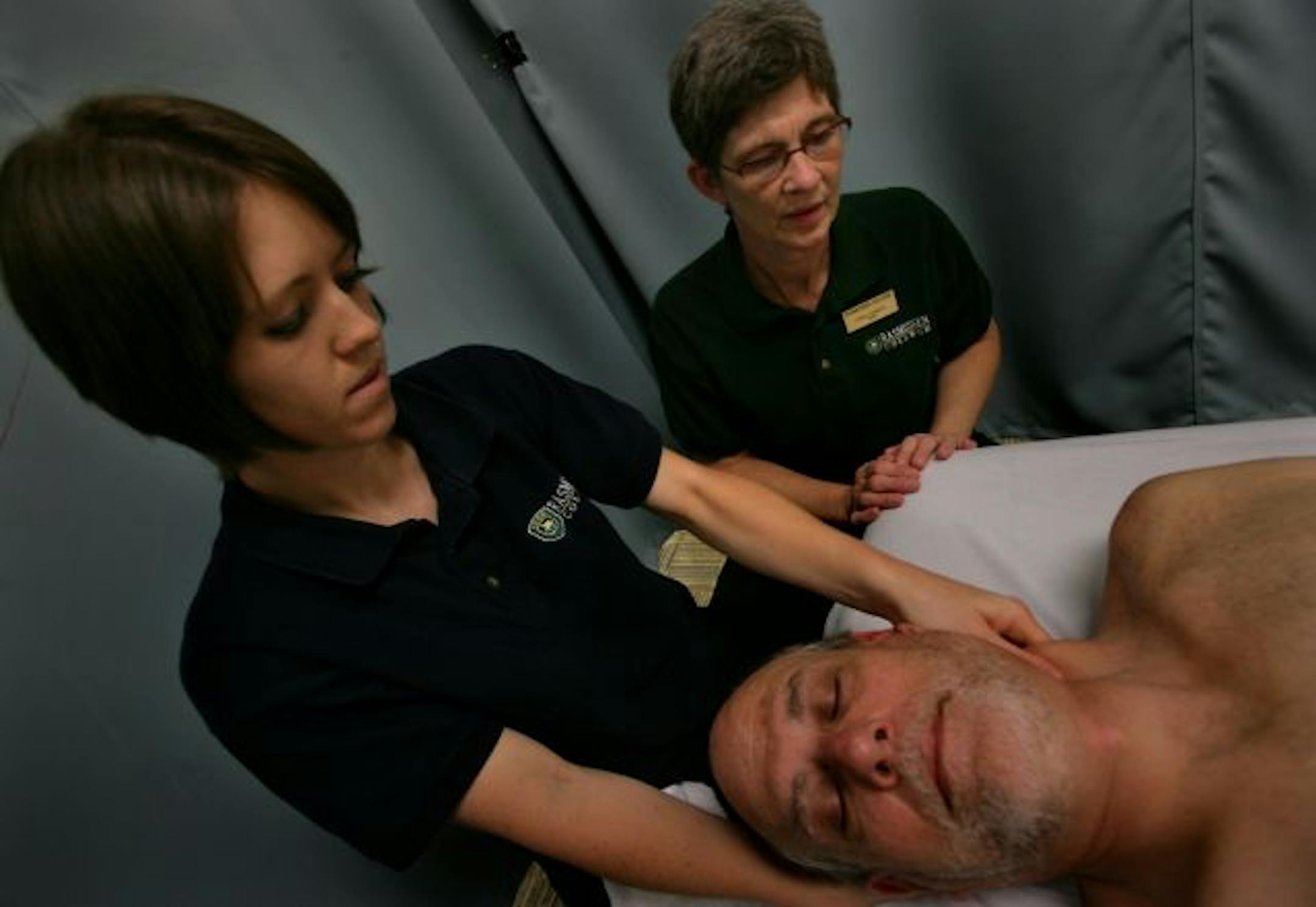 Massage Therapy Instructor Terry Clements instructs student Ashley Larson (left) on client Harvey Dicks during a session at Rasmussen College in Eden Praire, MN.