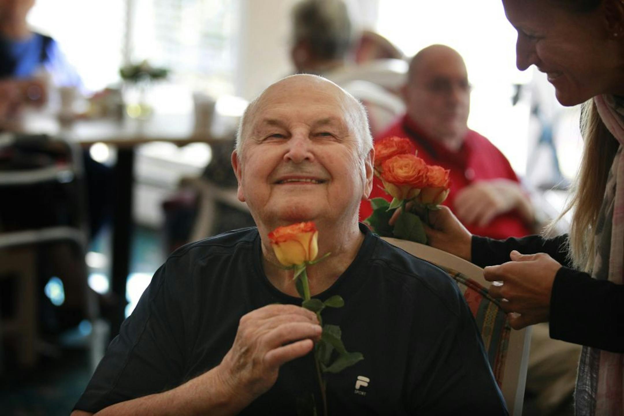 Dawn Vaillancourt left ,gave Bill Flesher a flower during a birthday celebration for residents of Walker Methodist Westwood Ridge community members who were born in October . Vaillancourt is the activities director at Westwood.
