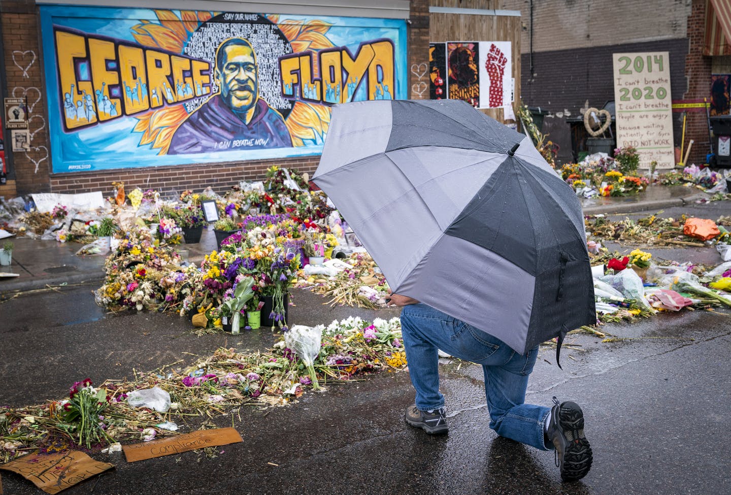 A man paused to kneel at the George Floyd memorial outside of Cup Foods. ] LEILA NAVIDI • leila.navidi@startribune.com BACKGROUND INFORMATION: A rainy afternoon at the George Floyd memorial outside of Cup Foods in Minneapolis on Tuesday, June 9, 2020.