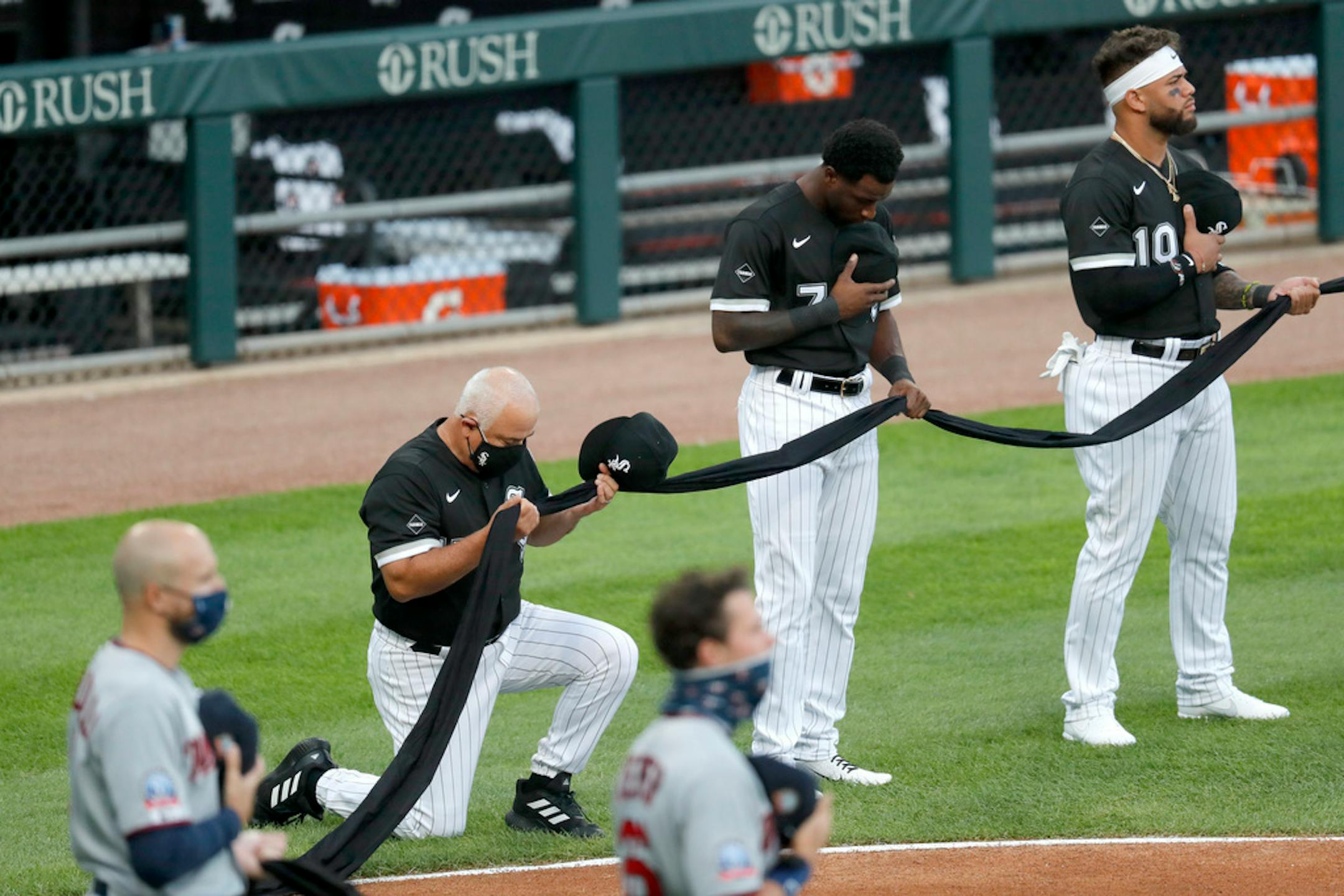 Chicago White Sox manager Ricky Renteria kneels for social justice next to Tim Anderson (7) and Yoan Moncada before a baseball game against the Minnesota Twins, Friday, July 24, 2020, in Chicago.
