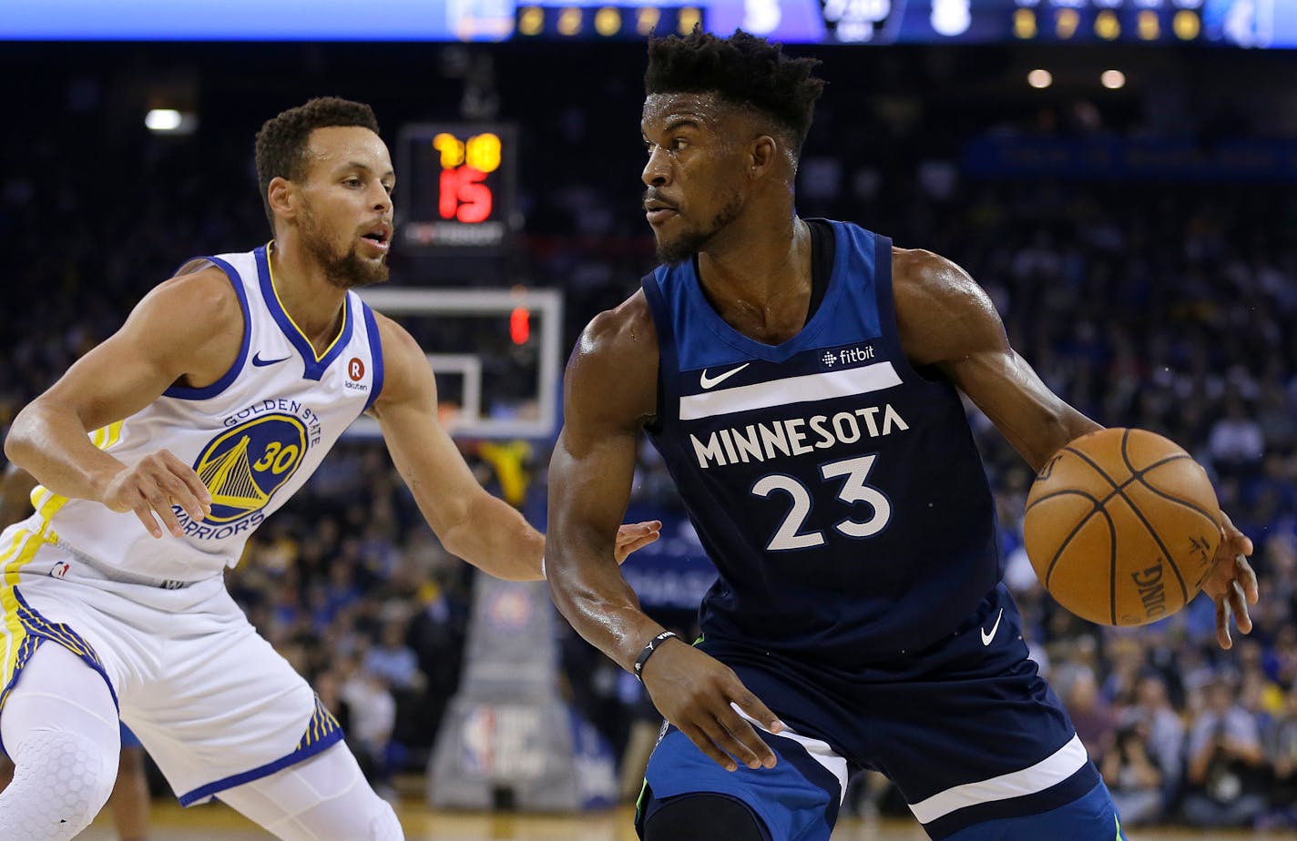 Minnesota Timberwolves' Jimmy Butler, right, drives the ball against Golden State Warriors' Stephen Curry (30) during the first half of an NBA basketball game Wednesday, Nov. 8, 2017, in Oakland, Calif. (AP Photo/Ben Margot)