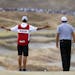 Phil Mickelson, right, and caddie Jim "Bones" Mackay look over the second hole during the first round of the U.S. Open golf tournament at Chambers Bay
