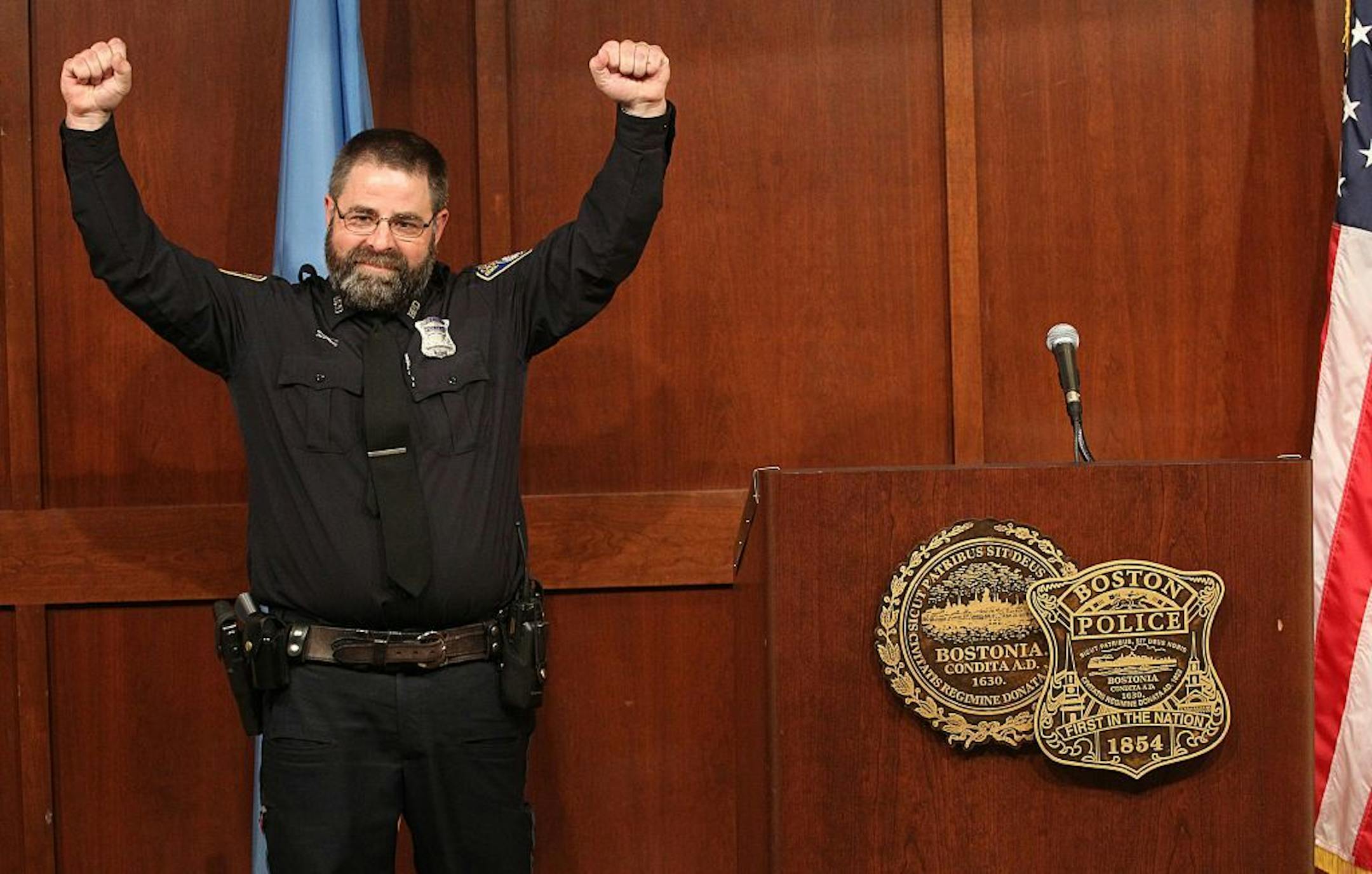 Boston Police Officer Steve Horgan, raises his hands as he poses for a photograph during a news conference on Tuesday, Oct. 15, 2013 in Boston. Horgan says he's humbled by the attention he's received since photographs of him raising his arms in jubilation after the Boston Red Sox hit a grand slam against the Detroit Tigers appeared in newspapers and on the Internet. The photos show Horgan's arms raised in the same frame as the upturned legs of Tigers outfielder Torii Hunter as he tumbles into th