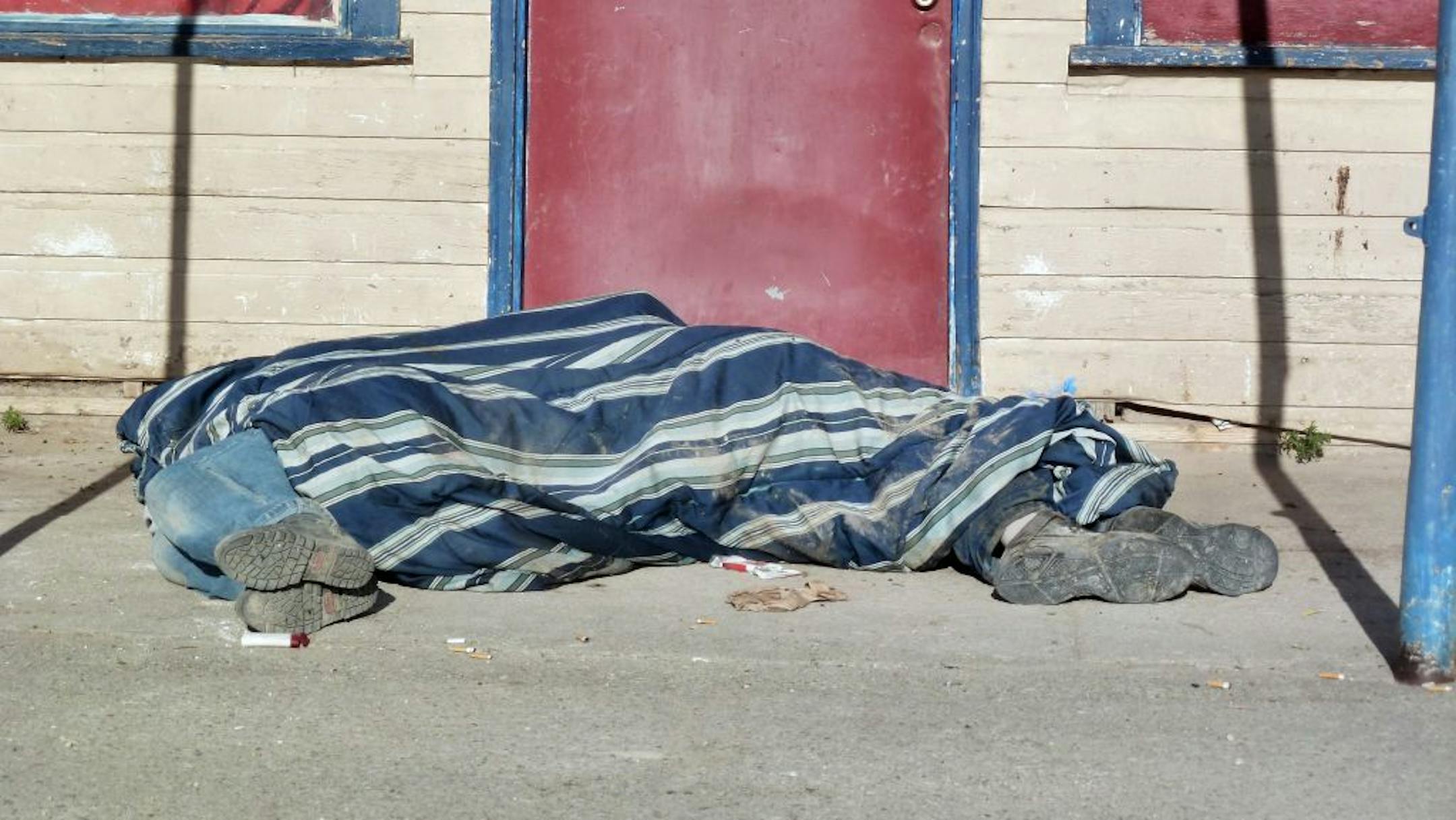 In this Aug. 9, 2013, photo homeless people cover themselves with a blanket on a street in Whiteclay, Neb. Many tribal members live on the tiny town's barren streets to avoid arrest on the nearby reservation for being drunk.